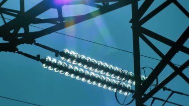 Mavi gökyüzünde güneş ışınları olan elektrik hatları. Yüksek voltaj santrali. Dünya 'da elektrik krizi. Elektrik hatlarında yeşil enerji. Seçici yumuşak odak