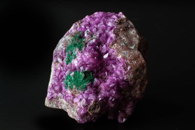 Siyah bir yüzeye izole edilmiş koyu yeşil malakit kristal makrosu olan canlı pembe kobalto kalsit.