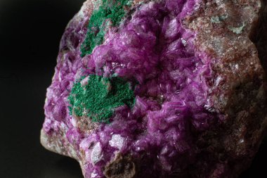 Siyah bir yüzeye izole edilmiş koyu yeşil malakit kristal makrosu olan canlı pembe kobalto kalsit.