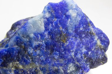 Beyaz arka planda çiğ Lapis Lazuli kayası. Beyaz arka planda cilalanmamış bir lapis lazuli yığını. Altın piriti lekeleri ve beyaz kalsit damarlarıyla koyu mavi Lapis lazuli. Altın ve beyaz detaylarla Ultramarine Rock.
