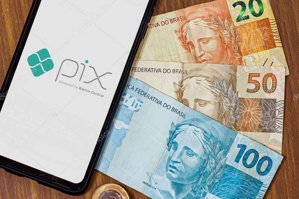 Sao Paulo, Brazil. MARCH 8, 2022: Pix logo on smartphone screen with multiple coins around. Pix is the new payment and transfer system of the Brazilian and Brazilian government.