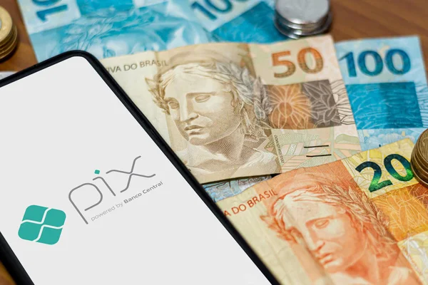 Sao Paulo, Brezilya. Pix logosu akıllı telefon ekranında ve etrafında birden fazla bozuk para var. Pix, Brezilya ve Brezilya hükümetinin yeni ödeme ve transfer sistemi..