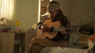 hiç logosu ya da markası olmayan genç beyaz bir kızın müzik yaşam tarzı klasik gitar çalıyor sıcak günbatımı ışığı olan pencerenin yanında logo ya da marka yok.