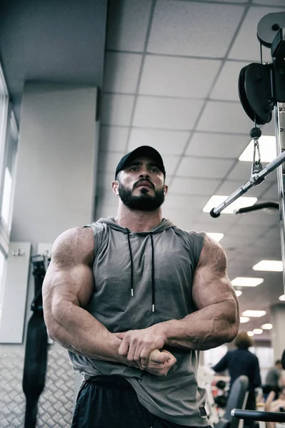 Silny młody kaukaski mężczyzna z broda pokazując silny mięśnie wewnątrz siłownia — Zdjęcie stockowe