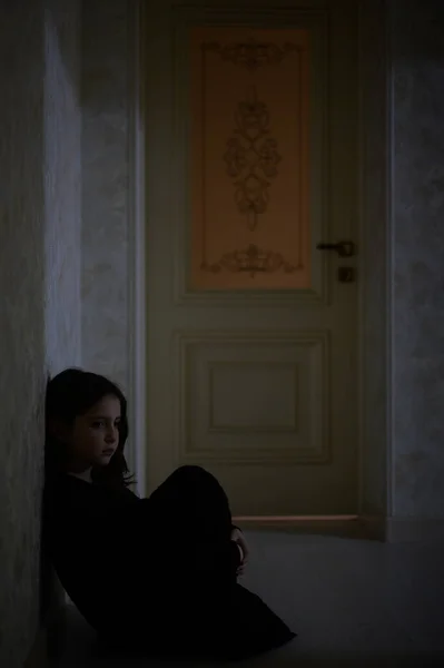 Τα δικαιώματα των παιδιών έννοια του μικρού αναστατωμένος θλιβερό μοναχικό κοριτσάκι με μαύρο φόρεμα κάθεται στο πάτωμα εσωτερικό δωμάτιο νύχτα — Φωτογραφία Αρχείου