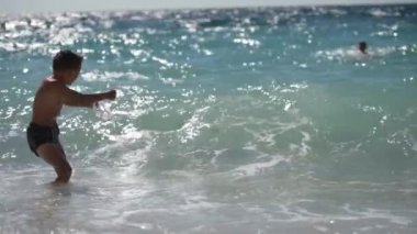 summer vacation leisure activity of little boy in diving mask fighting boxing against sea water storm waves