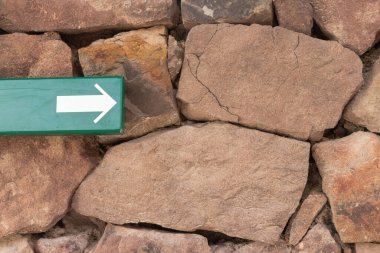 Yeşil etiketli kahverengi kaya duvar ve beyaz ok