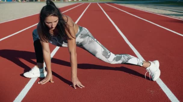 Mladá fena s neobvyklým vzhledem dělat strečink cvičení venku na sportovním hřišti, sportovec dělá cvičení. — Stock video