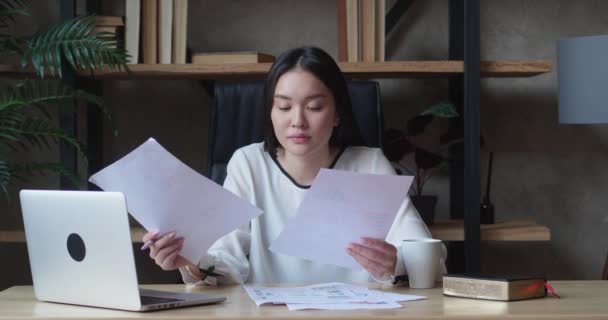 Une femme d'affaires a vu une erreur dans le rapport en regardant les documents commerciaux. La femme asiatique n'a pas terminé la tâche à temps et a fermé l'ordinateur portable. — Video