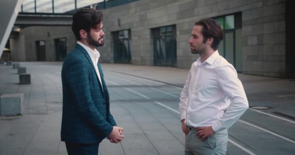 Twee vrolijke en succesvolle zakenpartners staan netjes gekleed op straat en lachen elkaar grappige verhalen te vertellen. — Stockvideo