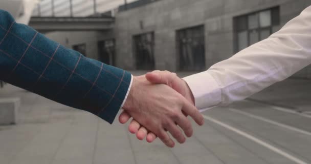 Dos hombres se dan la mano, celebran un acuerdo de contrato exitoso, señal de apoyo a la cooperación de asociación, empresarios bien vestidos saludan en la calle con gesto de armas masculinas. — Vídeos de Stock