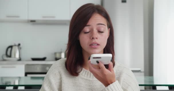 Close-up weergave van emotionele vrouw opnemen van een voice message op de telefoon zitten in gezellige bank in moderne kamer achtergrond. — Stockvideo