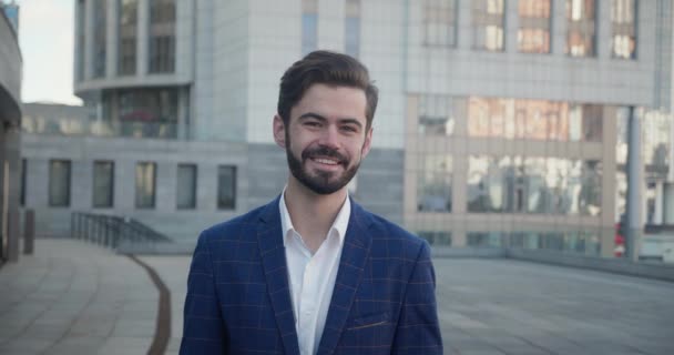 Portret van een lachende ondernemer met een baard in de buitenlucht in de straat, kijkend naar de camera. Leiderschap, stedelijke levensstijl en het concept van zakenmensen. — Stockvideo