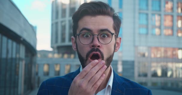 Um homem chocado com óculos e camisa dizendo wow cobrir sua boca com sua mão. — Vídeo de Stock