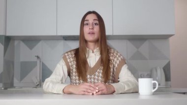 Gülümseyen genç yetişkin kadın vlogger kamera konuşmasına bak canlı video konferans görüşmesi yap bilgisayar uygulaması kayıt blogu vlog 'u kullanarak mutfakta otur, webcam görünümünü kapat, video kaset konseptini kapat.