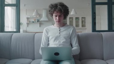 Stresli kıvırcık hippi ev ofisinde işini bitir, çok çalış, bilgisayarını kapat, bilgisayarını kapat, üniversitede uzaktan öğrenim al.