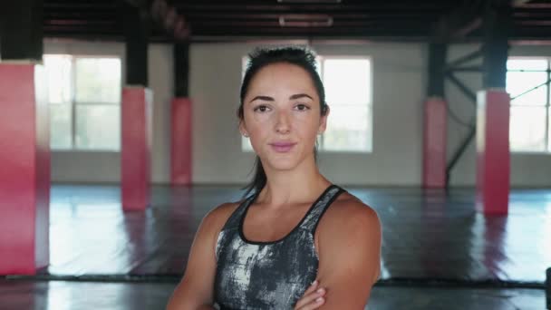 Fiatal női fitness guru áll a tornateremben keresztbe tett karokkal és a kamerába néz. Egészséges ifjúság, testápolás és aktív életmód koncepció — Stock videók