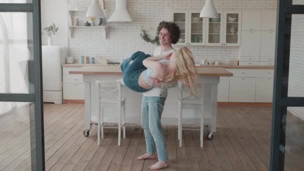 Guy spinning the girl in his arms. Young couple celebrating relocation together. Smiling curly man and blonde woman having fun at luxury house. Love couple hugging in new apartment. Slow motion — Video Stock