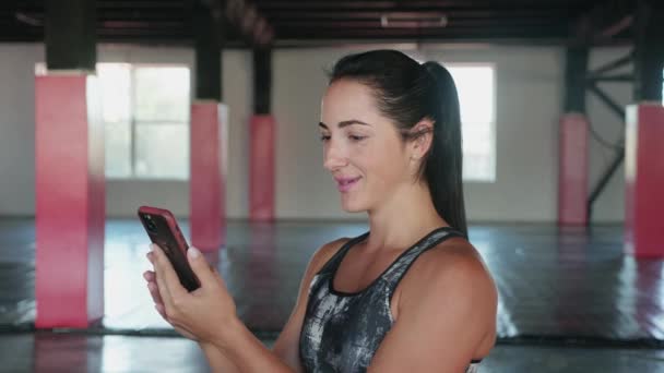 Fitness woman have video call with smart phone in gym. Woman using mobile phone while resting during fitness training — Vídeo de Stock
