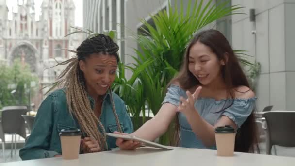 Asian and african american girls looking in screen ebook reading good news and celebrate win scream rejoices doing winner hands gesture — Stockvideo