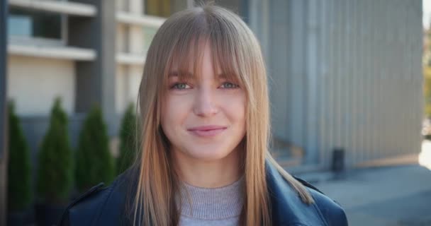 Amazed blonde woman shocked. Attractive girl amazed or surprised looking at the camera. She covers her mouth with her hand of the urban city background. — 图库视频影像