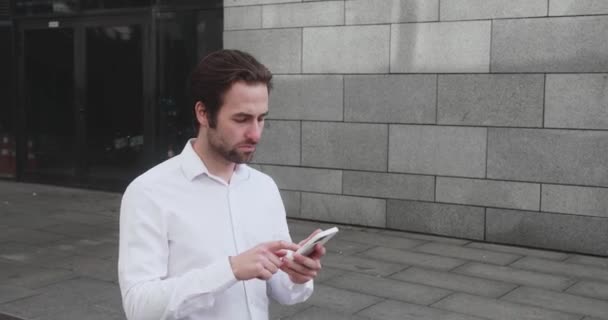 Young man texting Messages, cheating on his Smartphone while walking in Office District. Business. Social Networking. People. Apps. — Video Stock