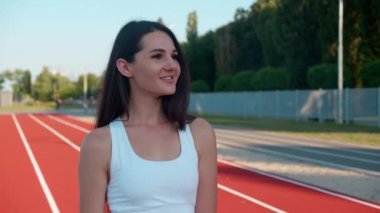 Kolları çaprazlanmış ve kameraya bakarak kırmızı spor pistinde duran kendine güvenen esmer kadın fitness gurusu. Sağlıklı gençlik, vücut bakımı ve aktif yaşam tarzı kavramı.