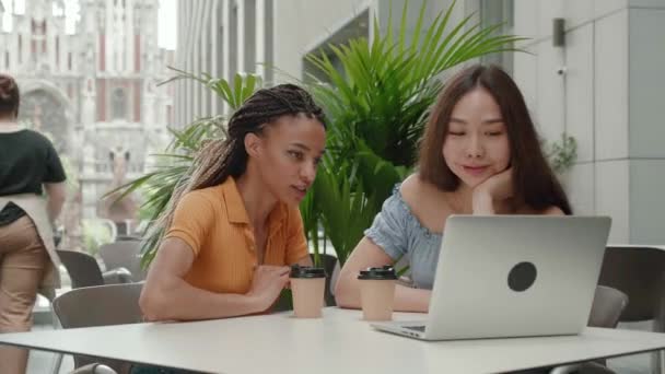 Asian girls and African American students Discussing at College campus on laptop - Concept of young people using technology for learning - young woman explaining to her colleague by looking on the — стоковое видео