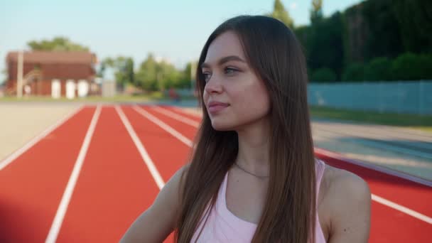 Confident young dark blond female fitness guru standing on red sports track with arms crossed and looking at camera. Healthy youth, body care and active lifestyle concept. — Wideo stockowe