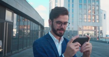 Oyunda akıllı telefondan oynayan ve şehir arka planında kaybeden çekici sıradan iş adamı.