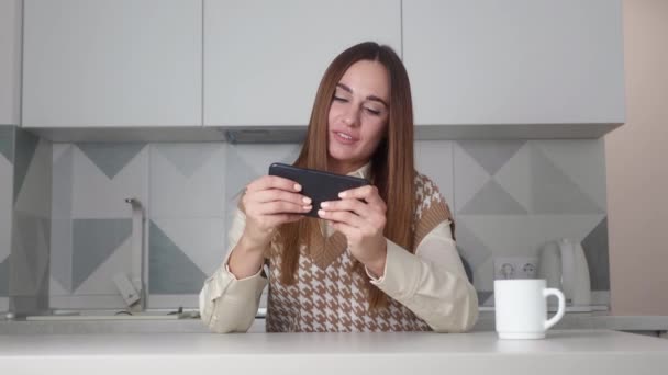 Millenaria seduta femminile con gioca uno smartphone. Donna che gioca gioco online su internet smartphone. Giovane ragazza viene sconfitta in un gioco online. Perdere il concetto. — Video Stock