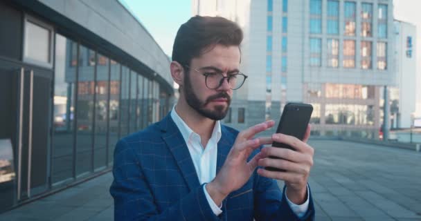 짜증나서 안 좋은 소식이야. 실망 한 고위 사업가가 스마트폰을 보고 야외에서 서 스트레스를 받는 모습. — 비디오