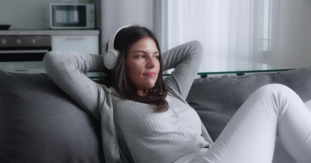 Serene femeie tânără atractivă care se odihnește pe canapea respirând adânc aer proaspăt ținându-se de mâini în spatele capului, o doamnă liniștită sănătoasă relaxându-se pe canapea confortabilă dormind se simt stresați singuri acasă — Videoclip de stoc