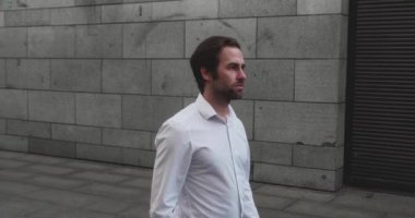 TS Genç Sakallı Kafkasyalı işadamı, açık alandaki modern iş binasının yanında yürürken. Büyük bir şehirde yoğun bir gün..