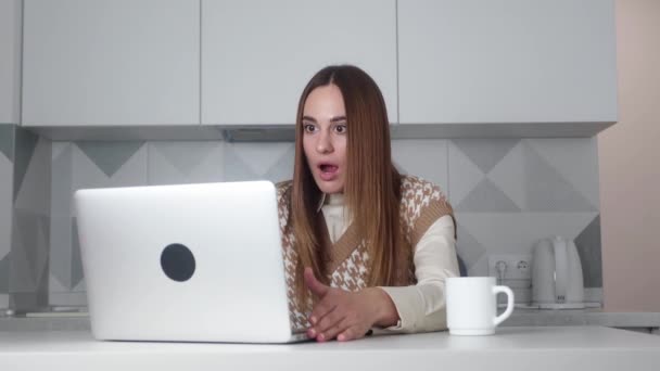 Astonished fun beautiful young woman girl 20s in vest looking surprised in screen laptop . People emotions lifestyle concept. Looking shocked surprised say wow put hands on face — стоковое видео