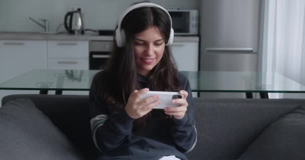 Молода жінка грає у відеоігри на своєму смартфоні і сердиться, коли програє гру — стокове відео