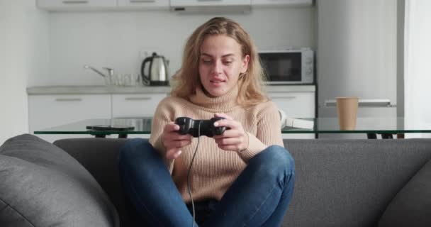 Çekici, kıvırcık saçlı, joystick ile video oyunu oynayan genç bir kadın. Kazanma konsepti. Ev eğlencesi. — Stok video