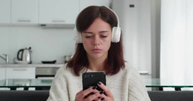 Millennial girl in headphone smiling and feeling happy to get good news from smartphone