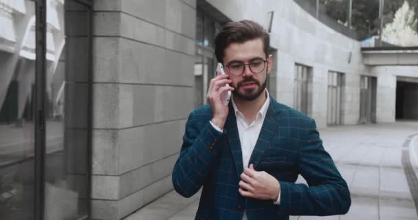 Successful businessman walking with phone at street. Confident man using smartphone outdoors. Serious business man using mobile phone outside — Vídeos de Stock