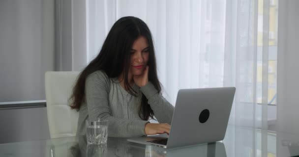 Young woman browsing news in social networks on a laptop sitting workplace at home office. Concept distance education or freelance — стоковое видео