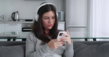 İnsanlar duygu konseptine hayran. Akıllı telefonlu bir kız koltukta otururken şok olmuş ve çok şaşırmış görünüyor. Vay canına de