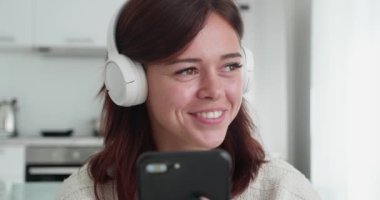 Bin yıllık kulaklıklı kadın cep telefonu kullanıyor ve gülümsüyor. Vay canına dedi.
