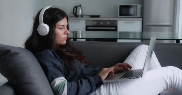 Jonge brunette vrouw in hoofdtelefoon afwerking werk op laptop. Tijd om te ontspannen — Stockvideo