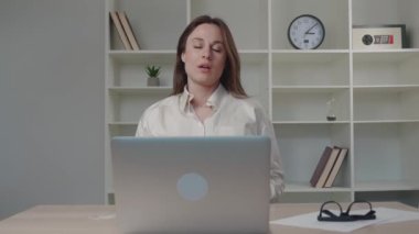 Genç Asyalı kadınlar stresten korunmak için ofiste otururken kaslarını esnetirler..