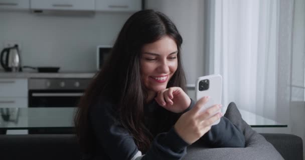 Kvinna koppla av på soffan sms med hjälp av smartphone surfa online spela mobilspel njuter av att dela meddelanden på sociala medier — Stockvideo