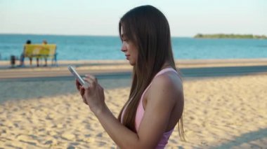 Stadyumda cep telefonu kullanan genç bir bayan. Spor kadını sonuçları kontrol ediyor