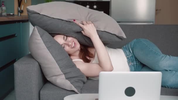 Młoda kobieta śpiąca na poduszkach pod kratą w łóżku wczesnym rankiem. Wściekła kobieta oburzona i zakrywająca głowę poduszką z powodu hałasu, który zakłóca sen. — Wideo stockowe