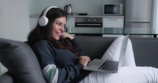 Fiatal vonzó diák nő videohívás távoli állásinterjú segítségével laptop webkamera konferencia munka feküdt kanapén otthon iroda. Happy Lady beszél virtuális chat találkozó társkereső online — Stock videók
