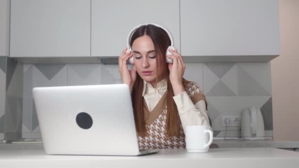 Cephede odaklanmış genç bir kadın ev ofisindeki bilgisayarda çalışıyor, müşterilerle iletişim kuruyor. Kulaklıkla çalışan başarılı bir kadın projeyle meşgul uluslararası şirket çalışanı. — Stok video
