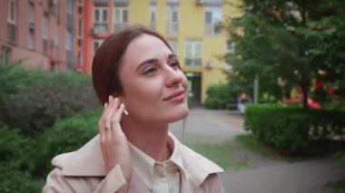 Kablosuz kulaklıklı genç işgücü kadını şehirde müzik dinliyor.